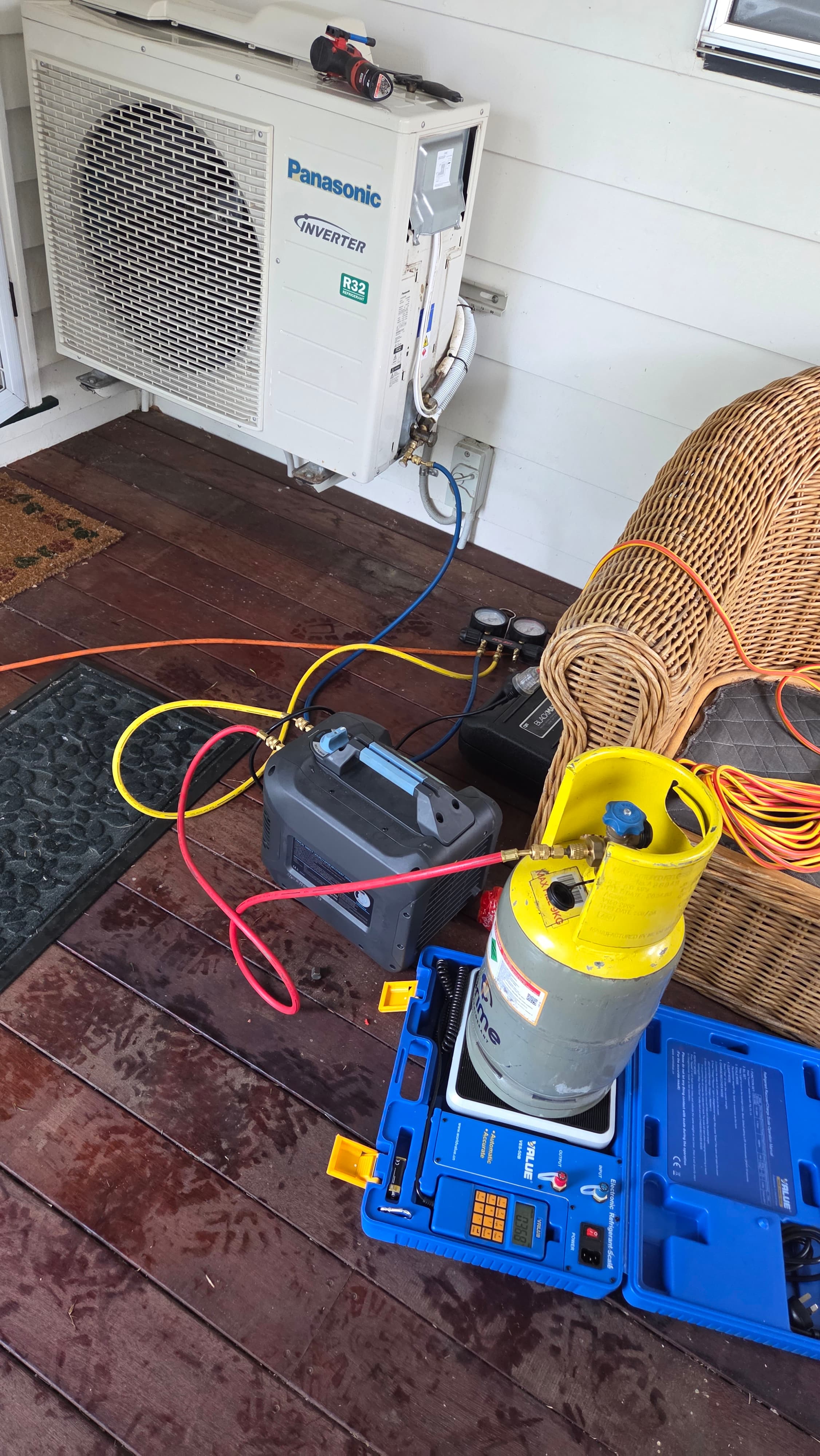 Refrigerant testing equipment set up beside an outdoor condenser unit during fault finding